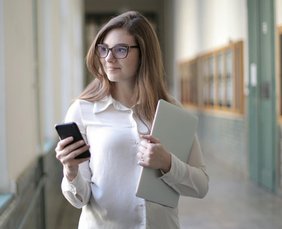 Person mit Mobile und Laptop in der Hand